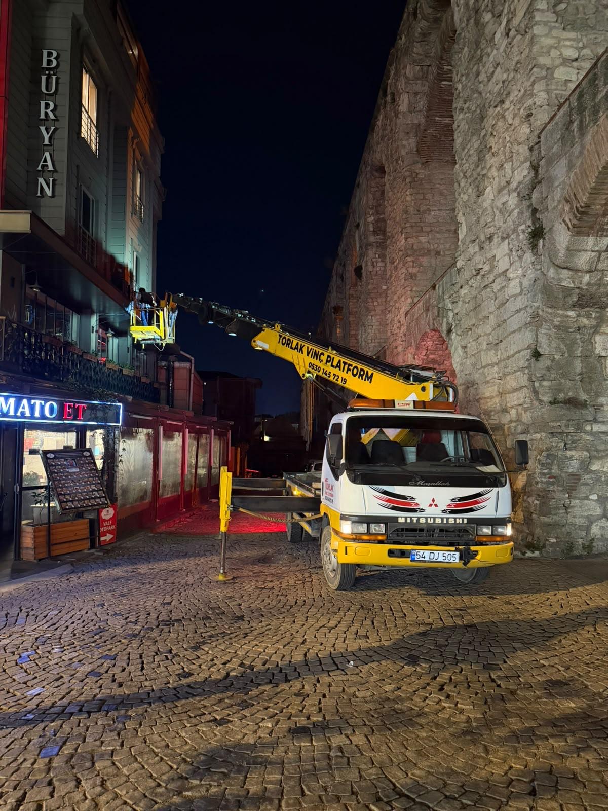 Gece, taş döşeli dar bir sokakta çalışan sepetli platform