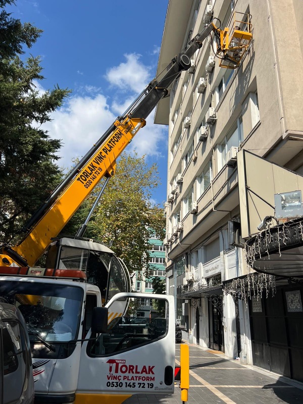 Yüksek bir apartman cephesinde, ağaçlı bir caddede çalışma