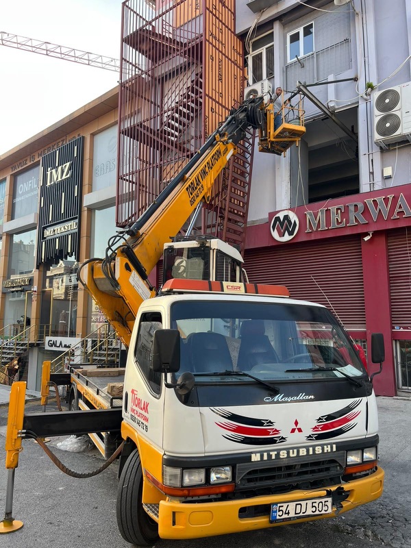 Ticari bir binanın cephesinde, tabela hizasında çalışan sepet