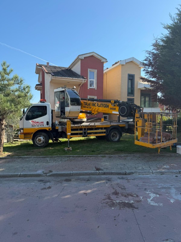Villa bölgesinde, çim alan kenarında kurulum yapan sepetli platform